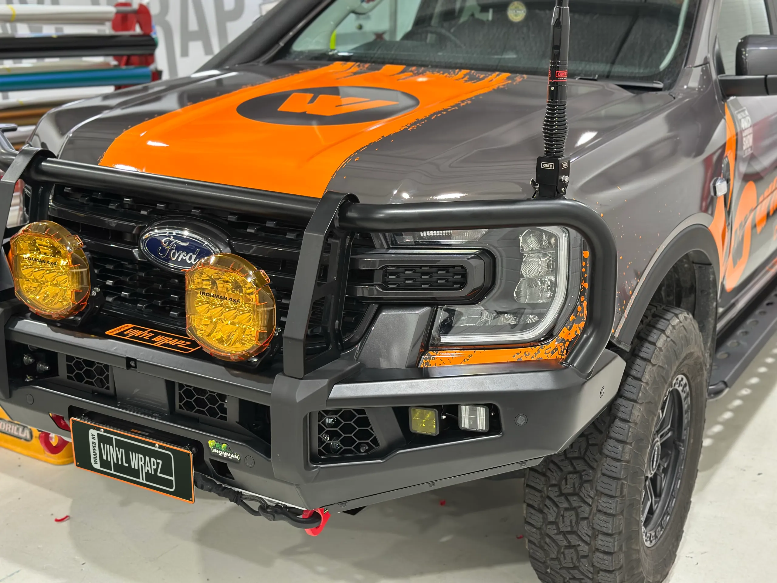Ford Ranger front quarter with orange and grey Wildtrak graphics, a bull bar and yellow driving lights