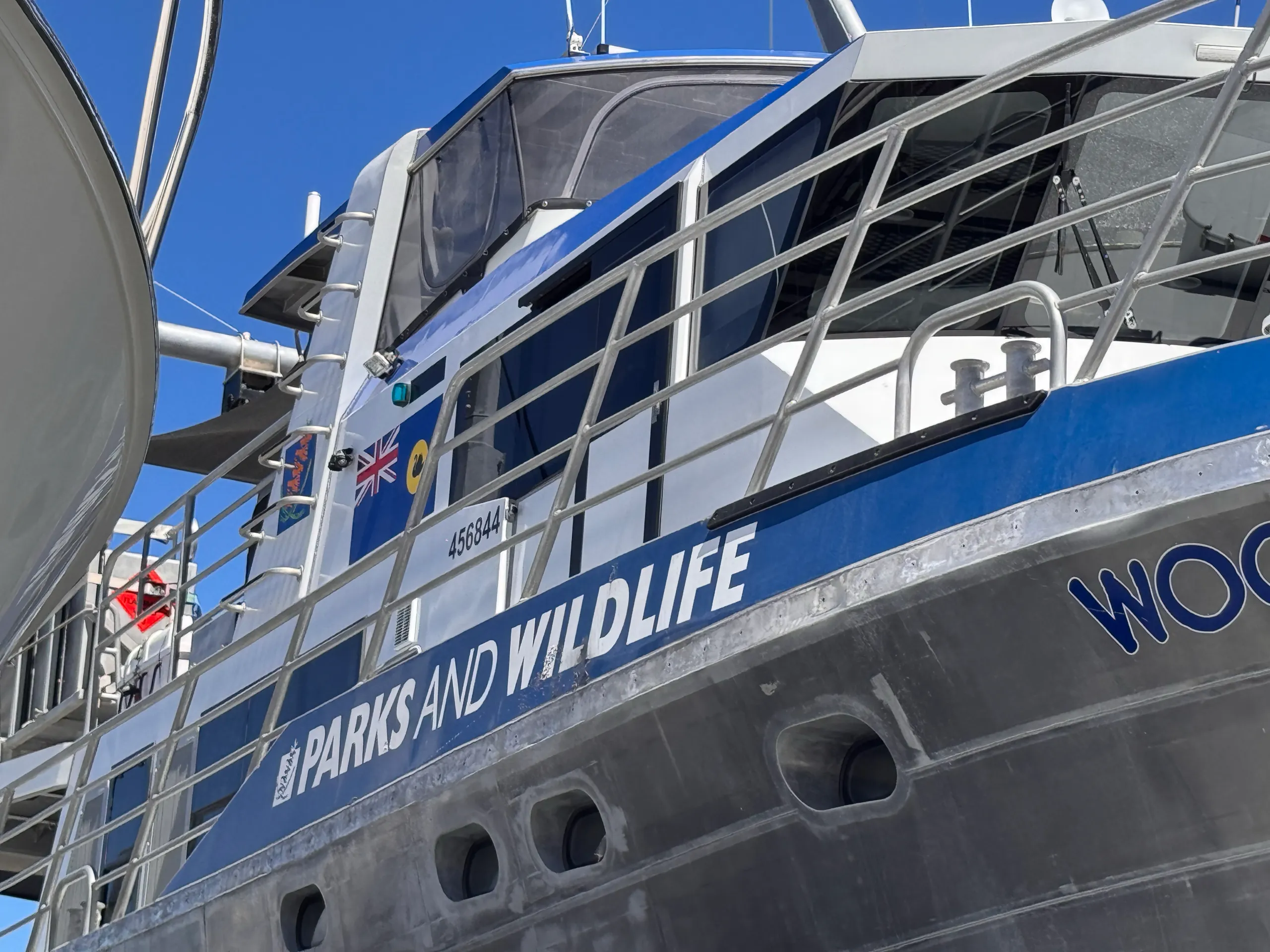 Blue and white Parks and Wildlife graphics along Woonbalu beneath its cabin railings