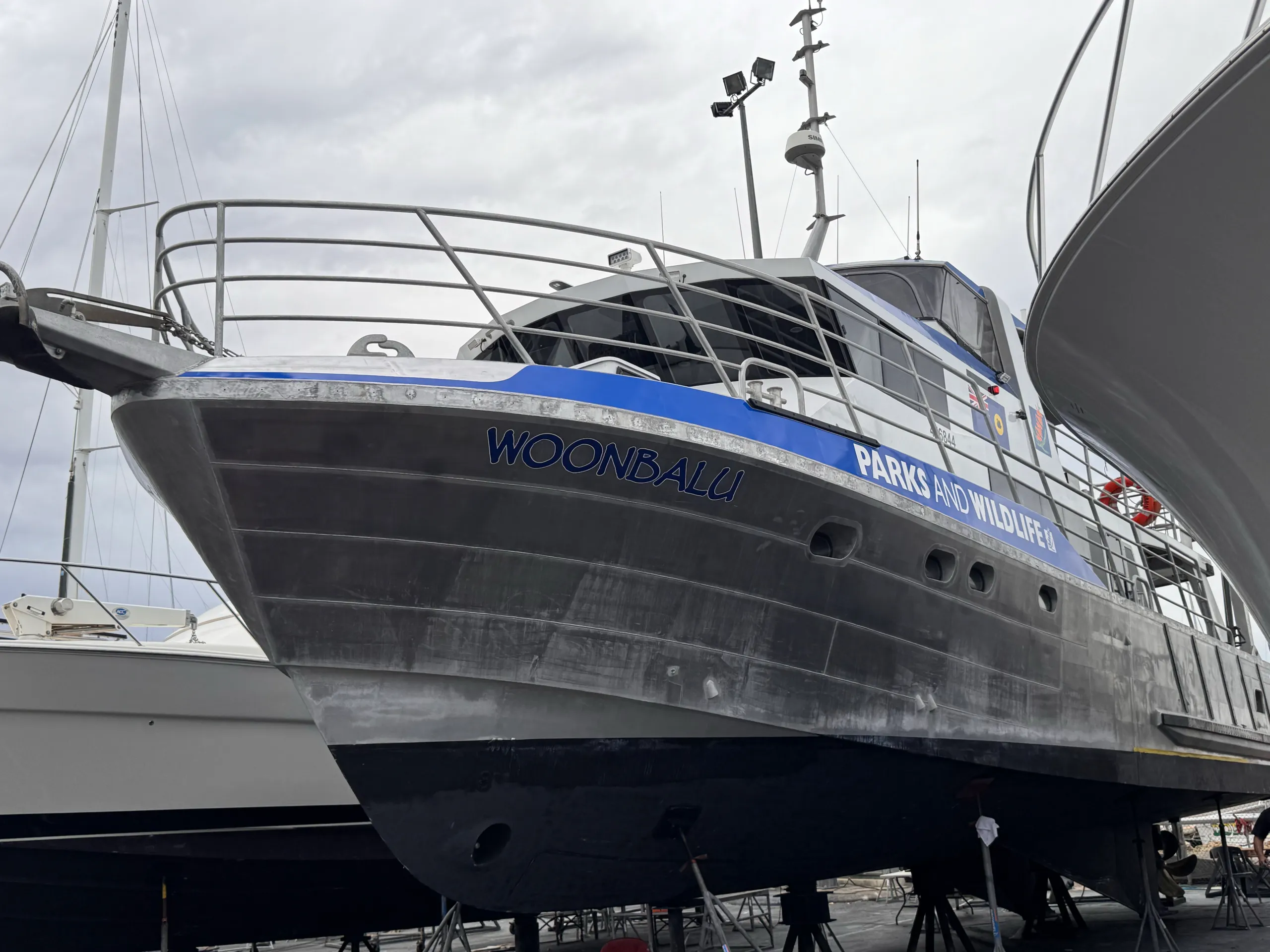 Woonbalu on boatyard stands with blue Parks and Wildlife branding along its bow and cabin