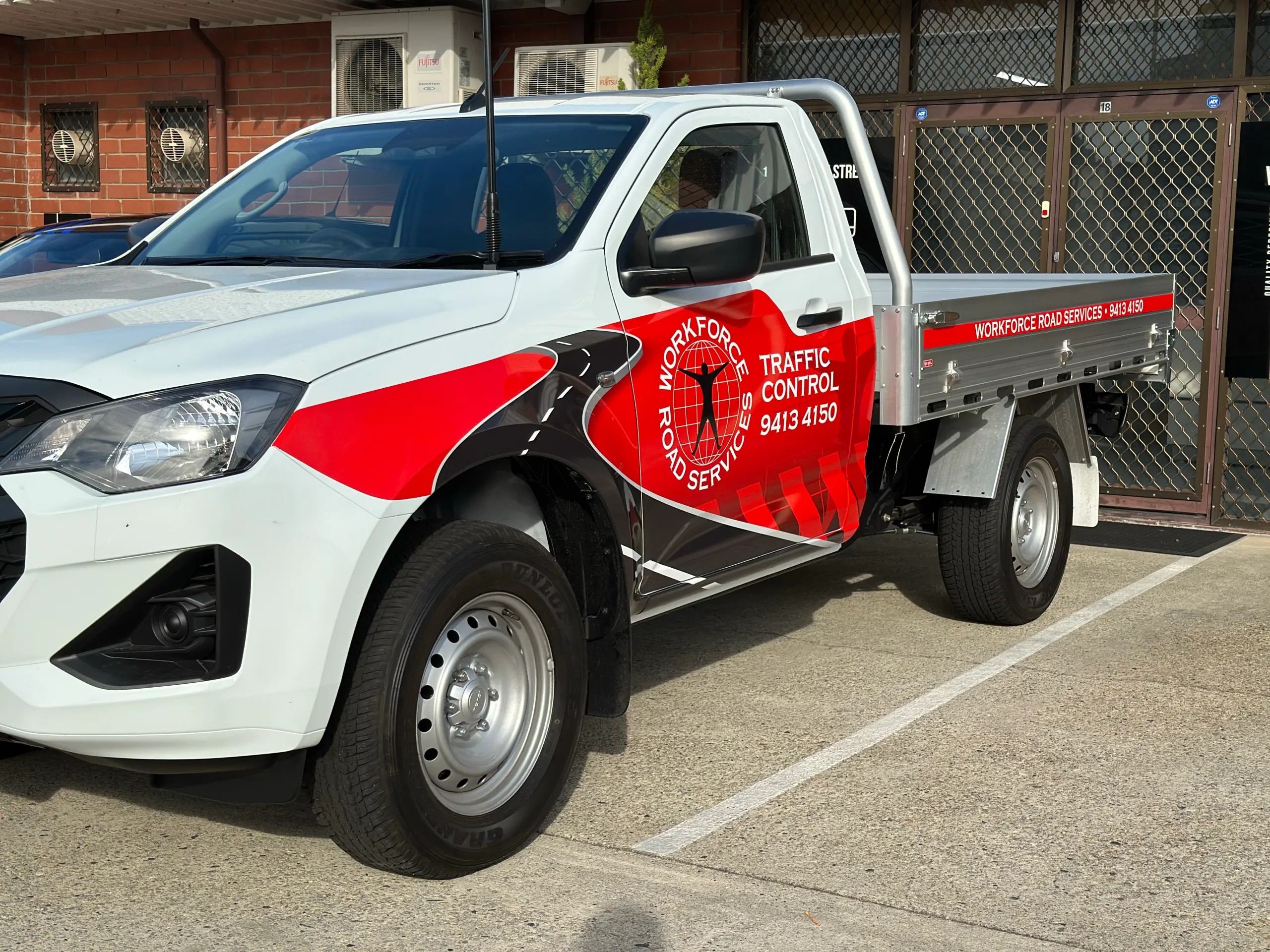 Front-quarter view of the white Workforce Road Services Isuzu D-MAX tray ute