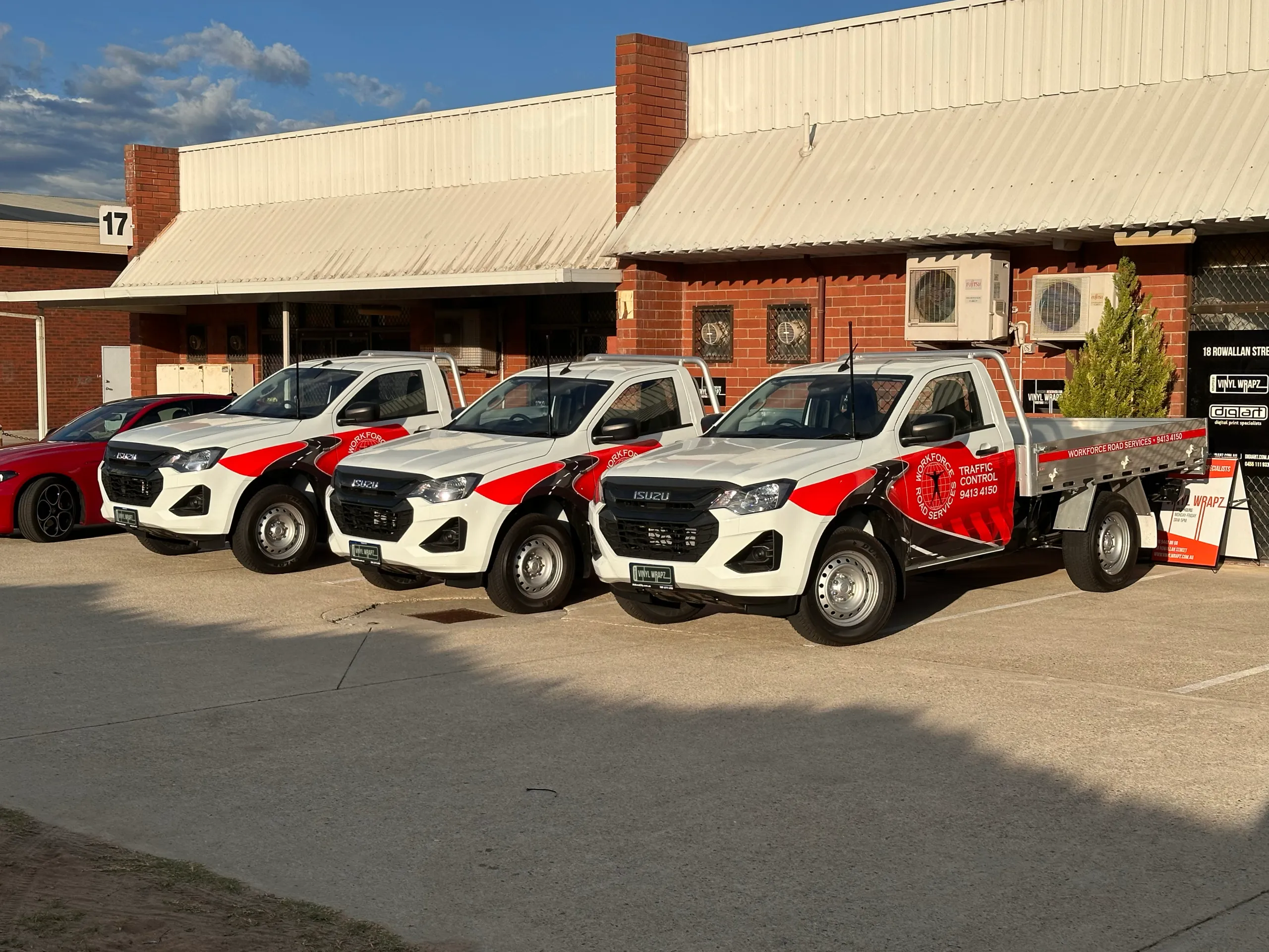 Workforce Road Services fleet of three white Isuzu tray utes with red and black graphics