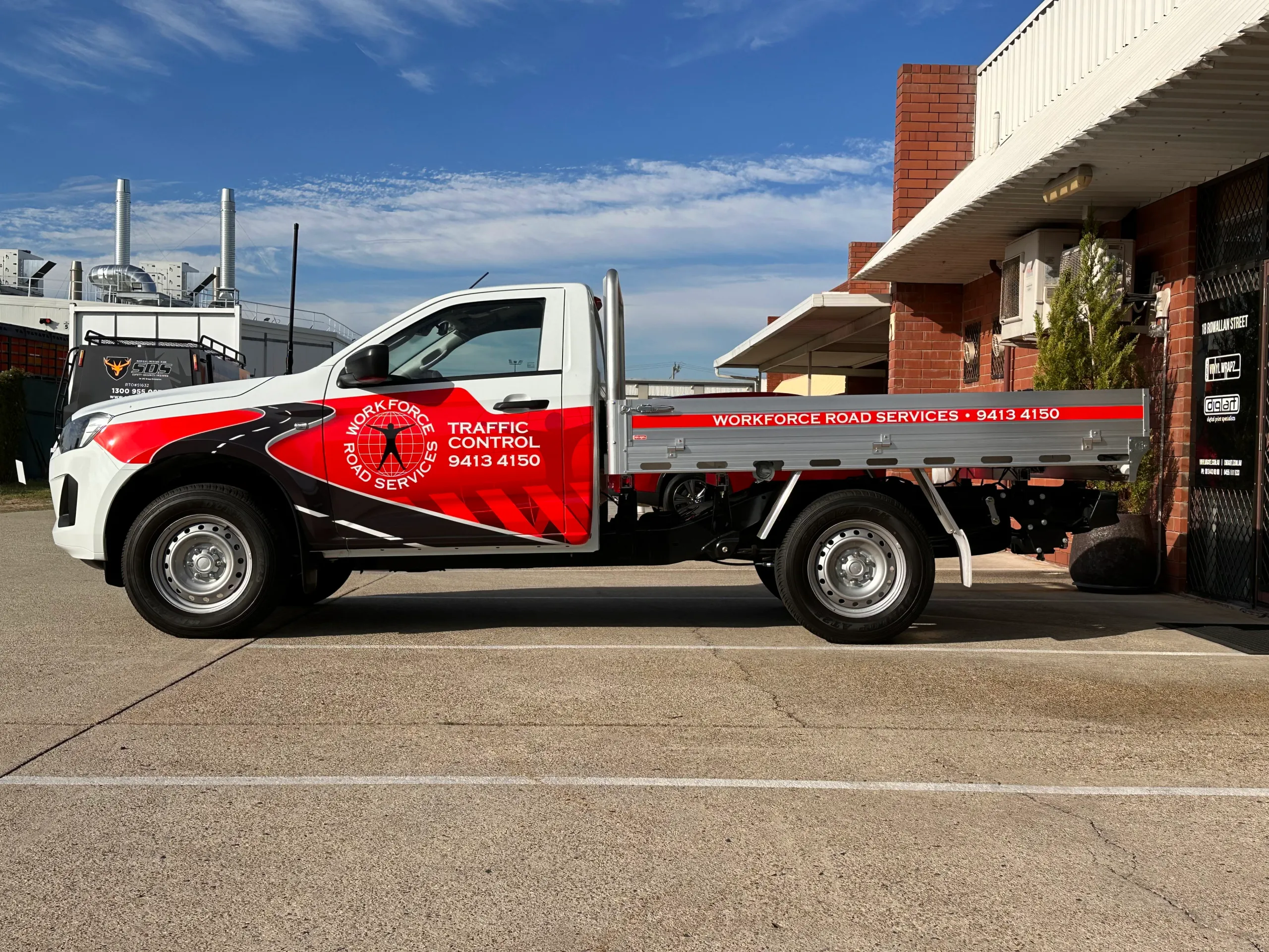 Workforce Road Services Isuzu tray ute with red and black graphics across its white cab