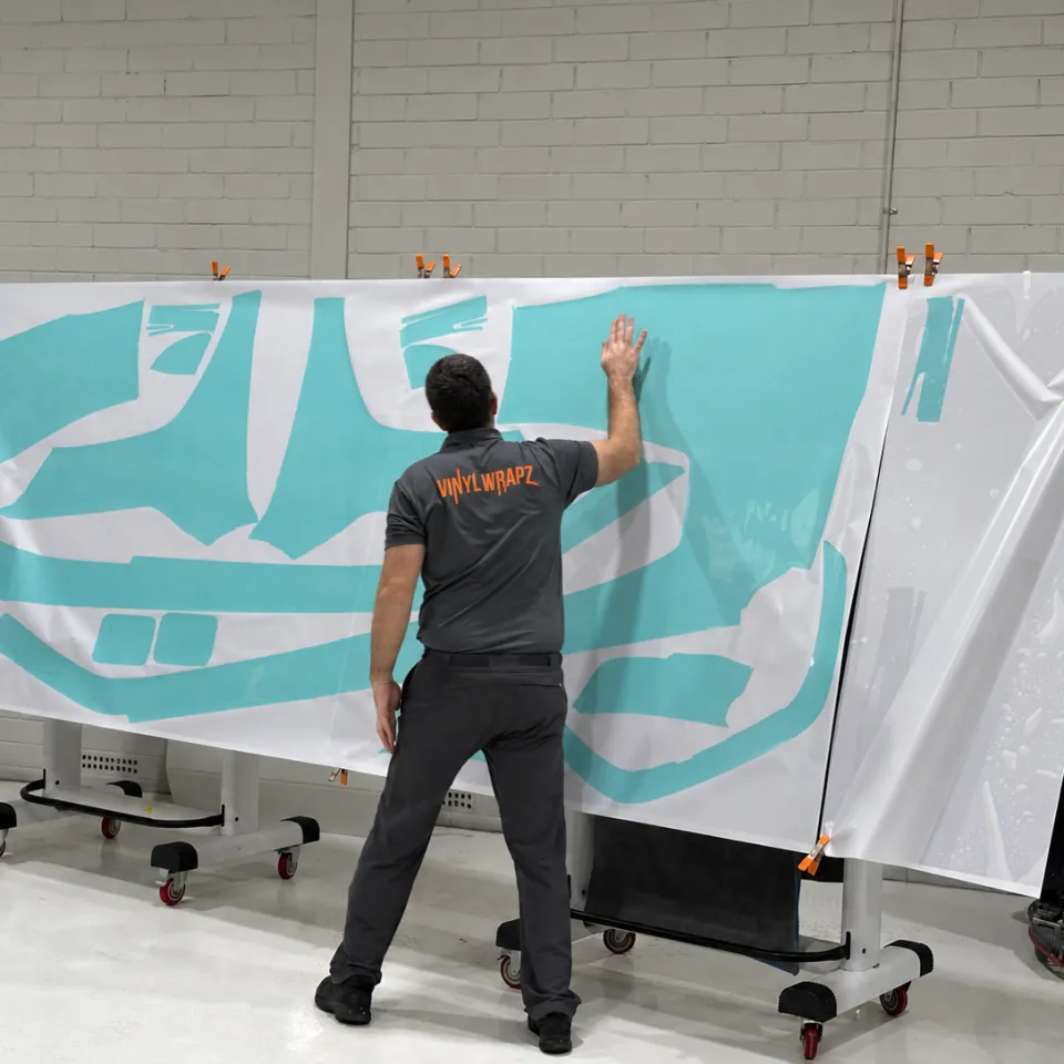 Installer facing away beside a sheet of cut film panels on a workshop stand