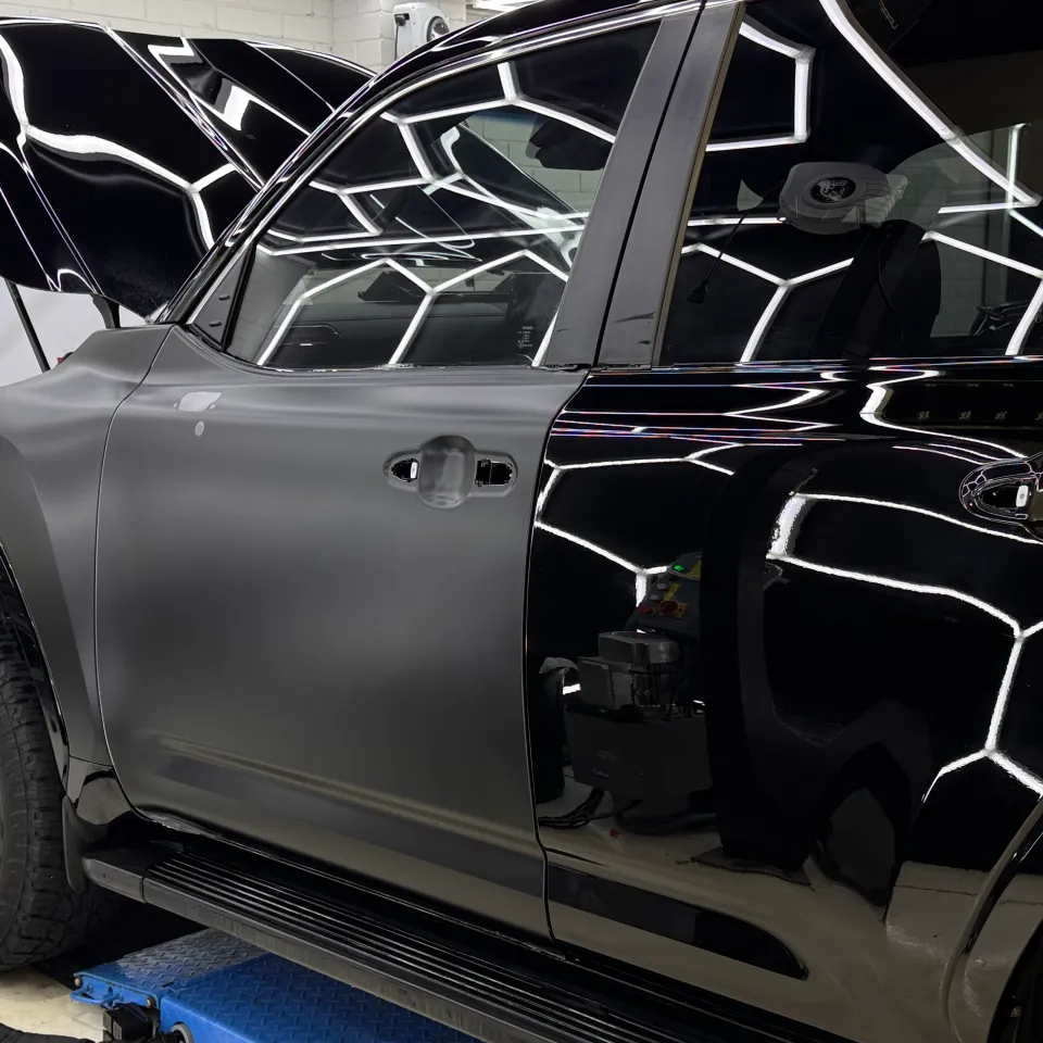 Satin film on a black ute front door during wrapping with its handles removed