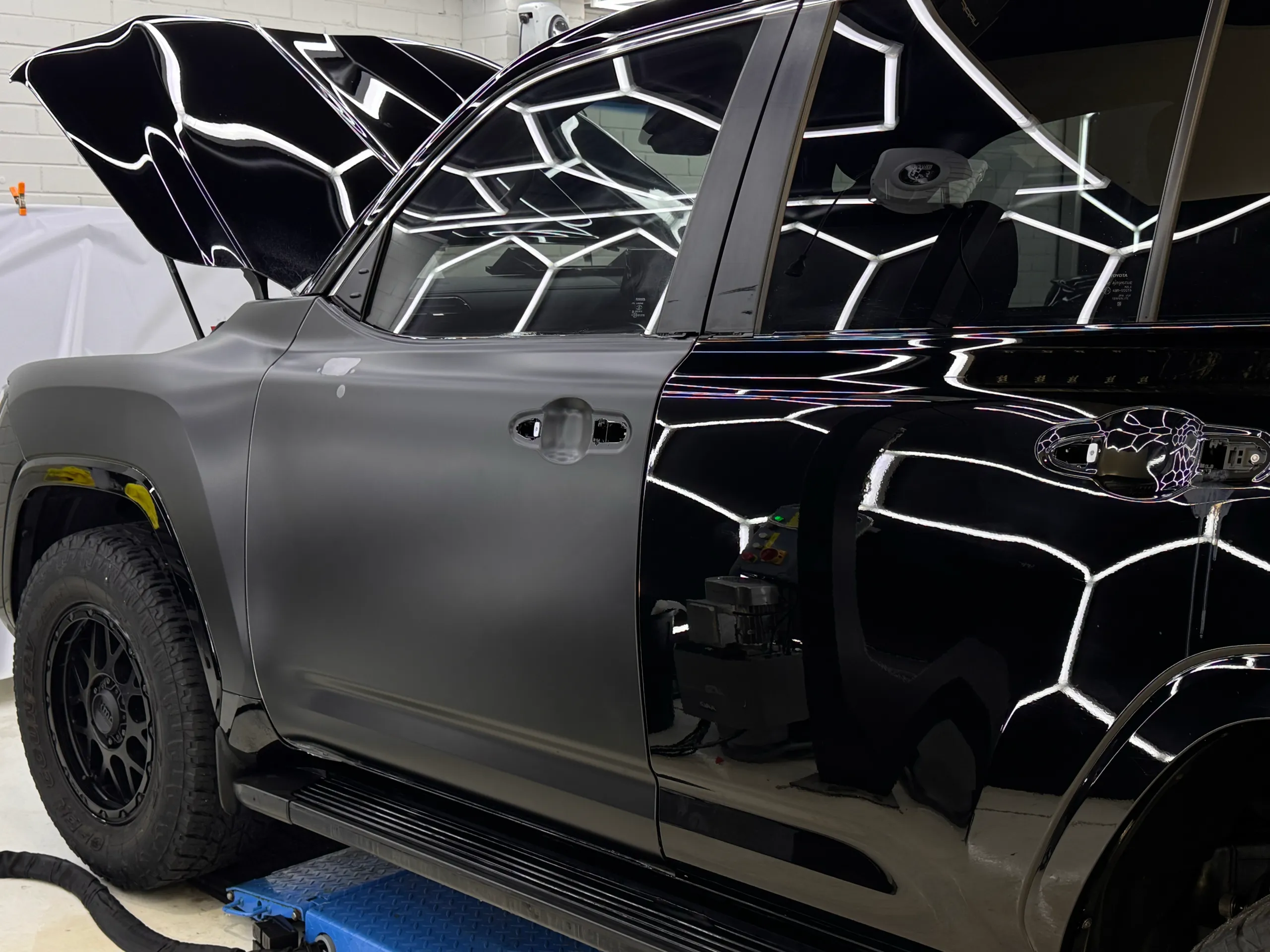 Satin film on a black ute front door during wrapping with its handles removed