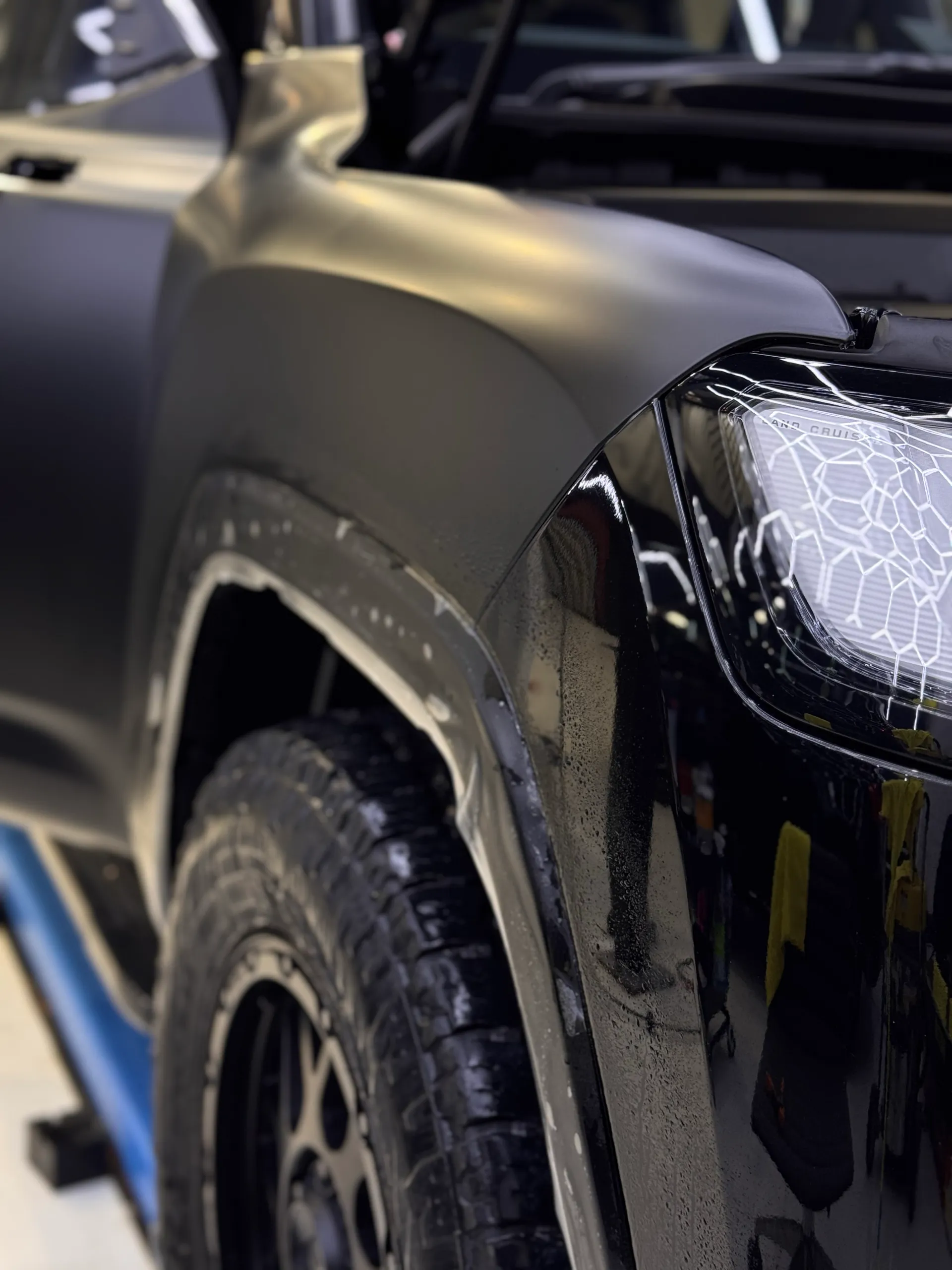 Satin film across a ute front guard during installation beside its headlight