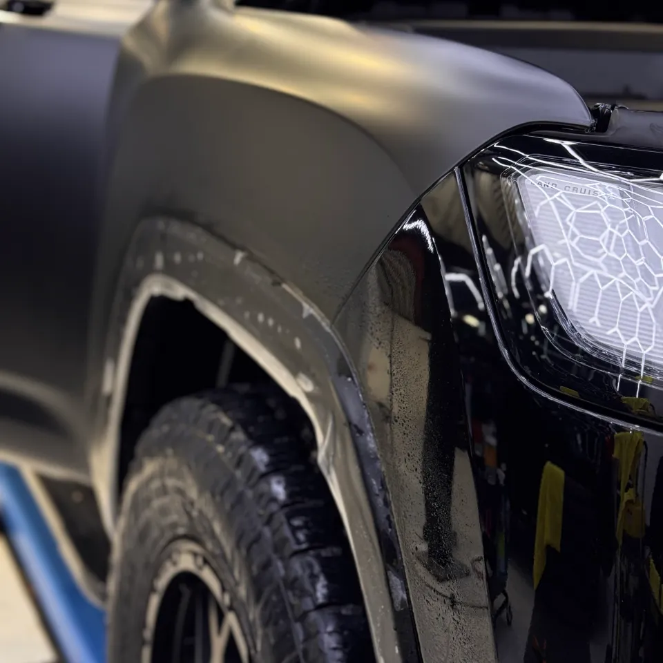 Satin film across a ute front guard during installation beside its headlight