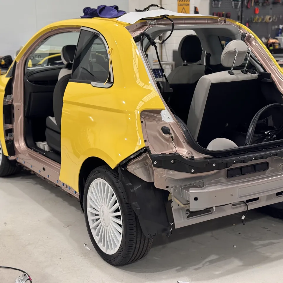 Yellow Fiat 500e rear during wrapping with boot lid and bumper removed