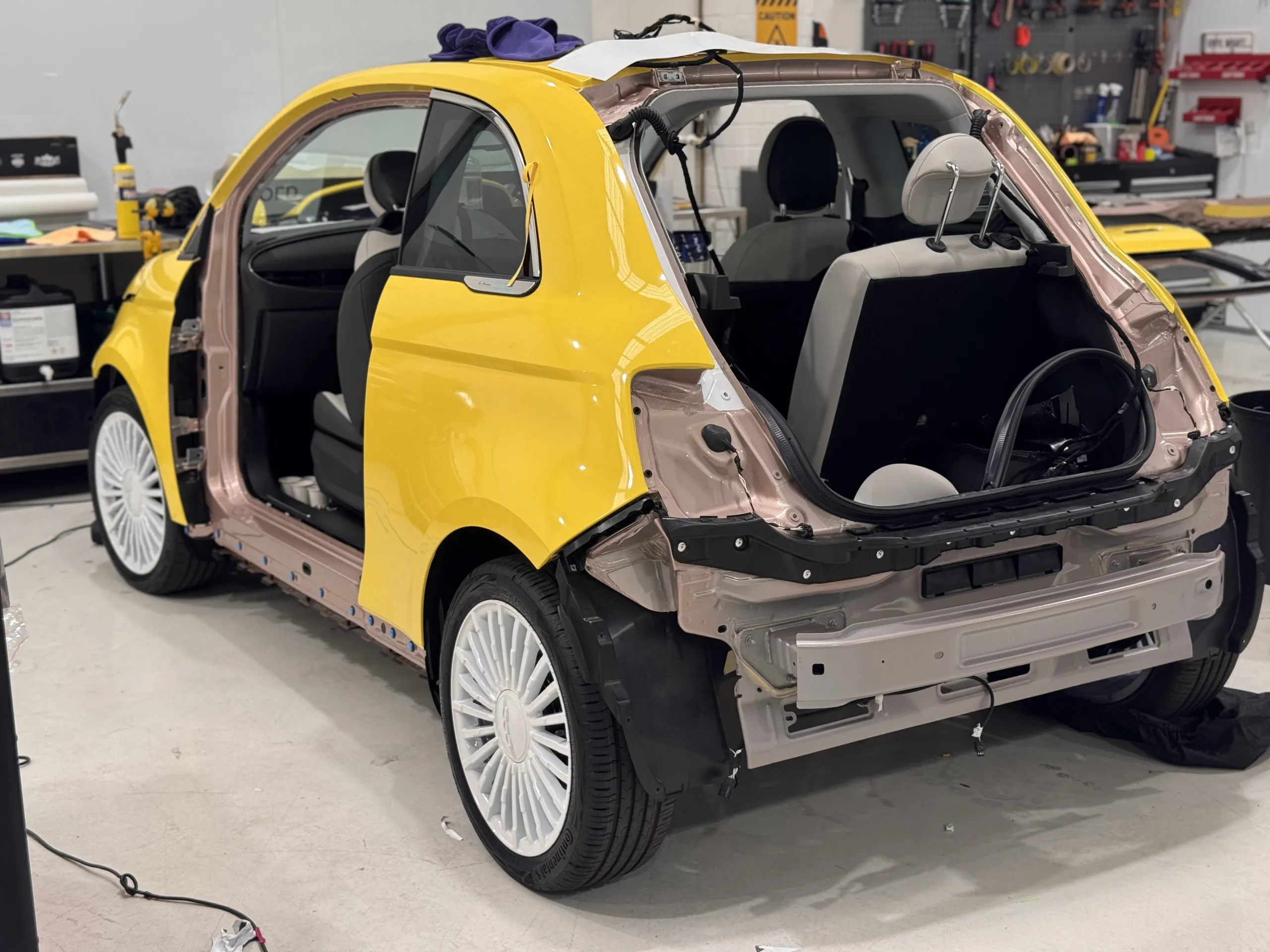 Yellow Fiat 500e rear during wrapping with boot lid and bumper removed