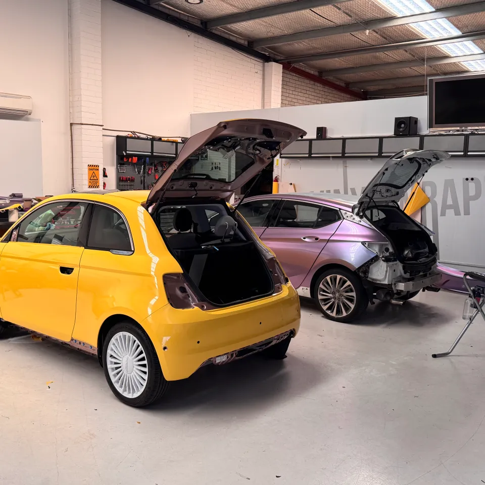 Yellow Fiat 500e and colour-shift Holden Astra with rear trim removed