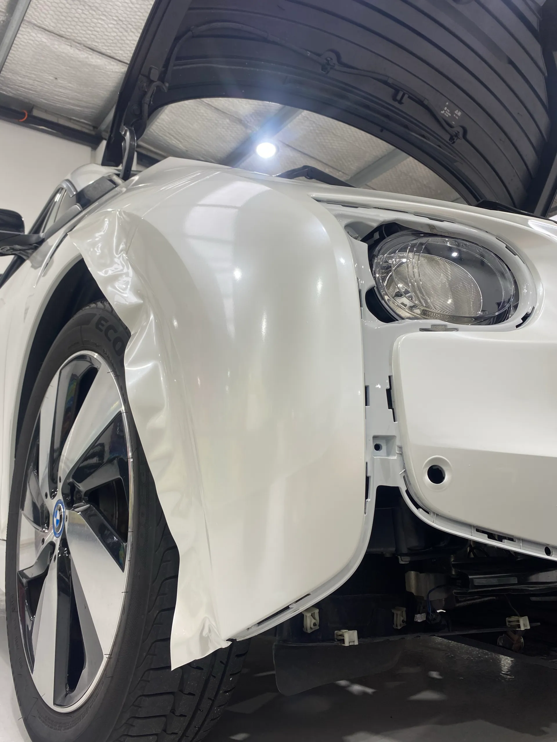 White film being fitted to a BMW i3 front wing with bumper removed