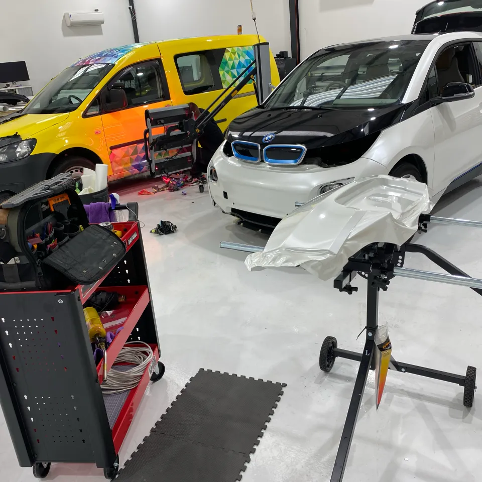 BMW i3 and yellow wrapped van with tools and loose film in the workshop