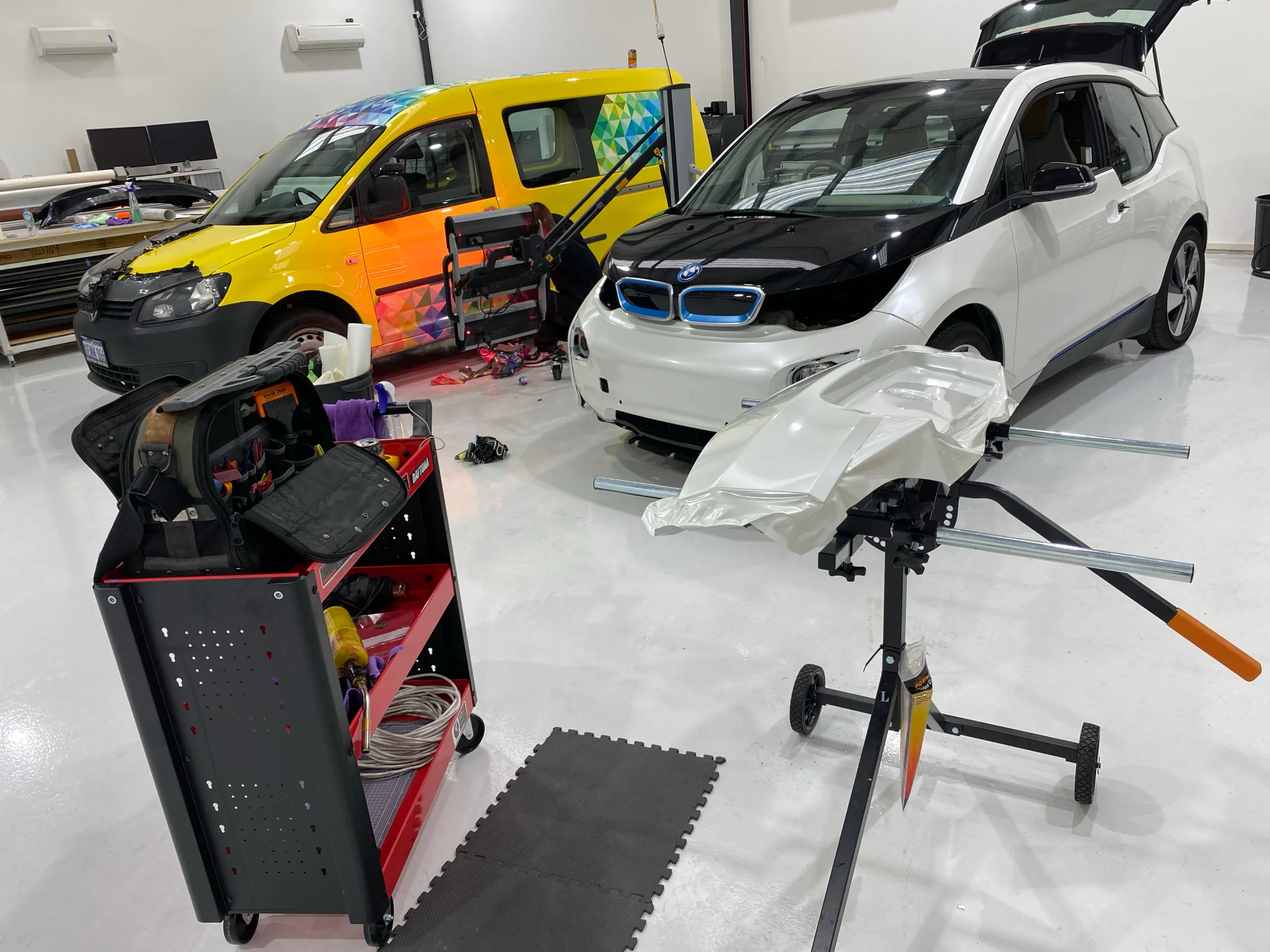 BMW i3 and yellow wrapped van with tools and loose film in the workshop