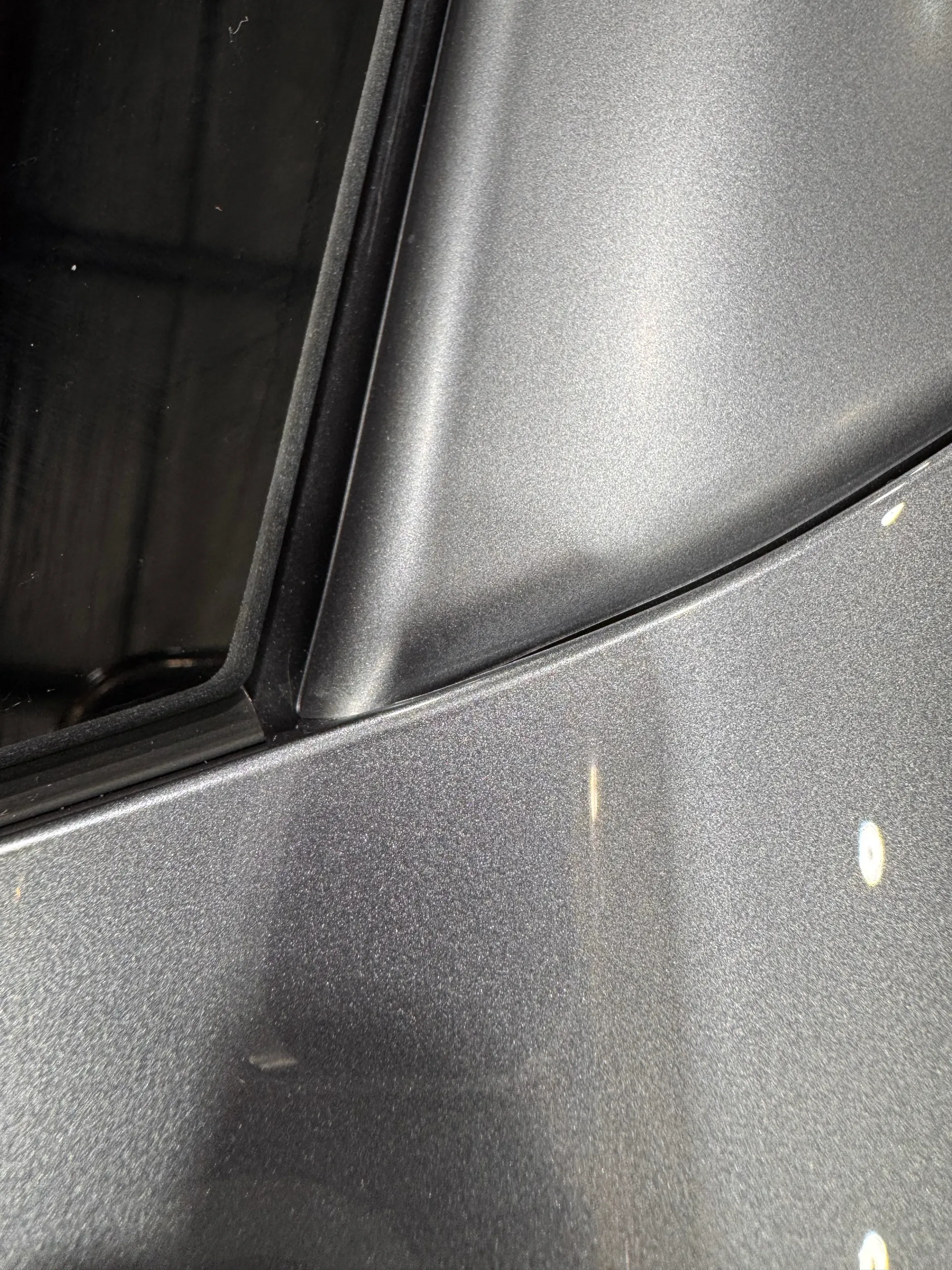 Grey wrapped pillar and adjoining body panel beside black window trim