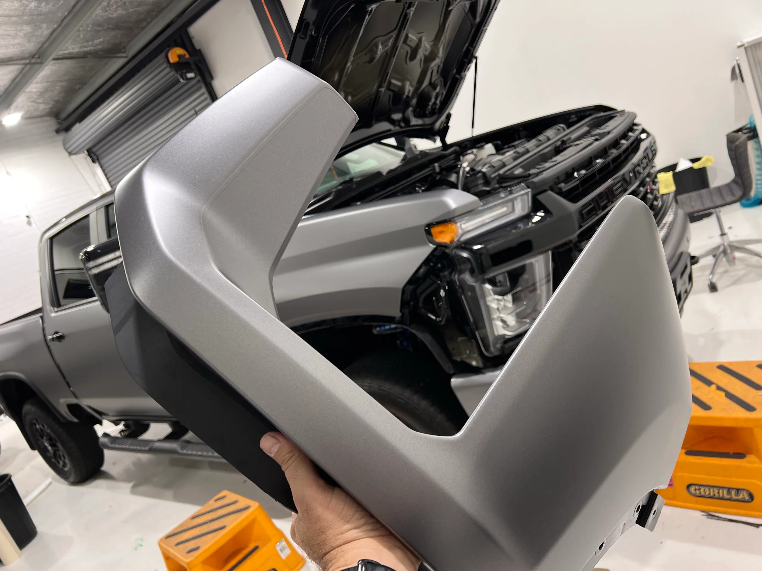Installer holding a silver wrapped panel beside a partly dismantled LandCruiser