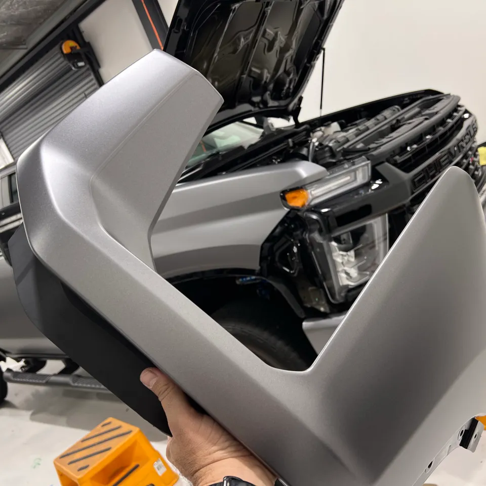 Installer holding a silver wrapped panel beside a partly dismantled LandCruiser