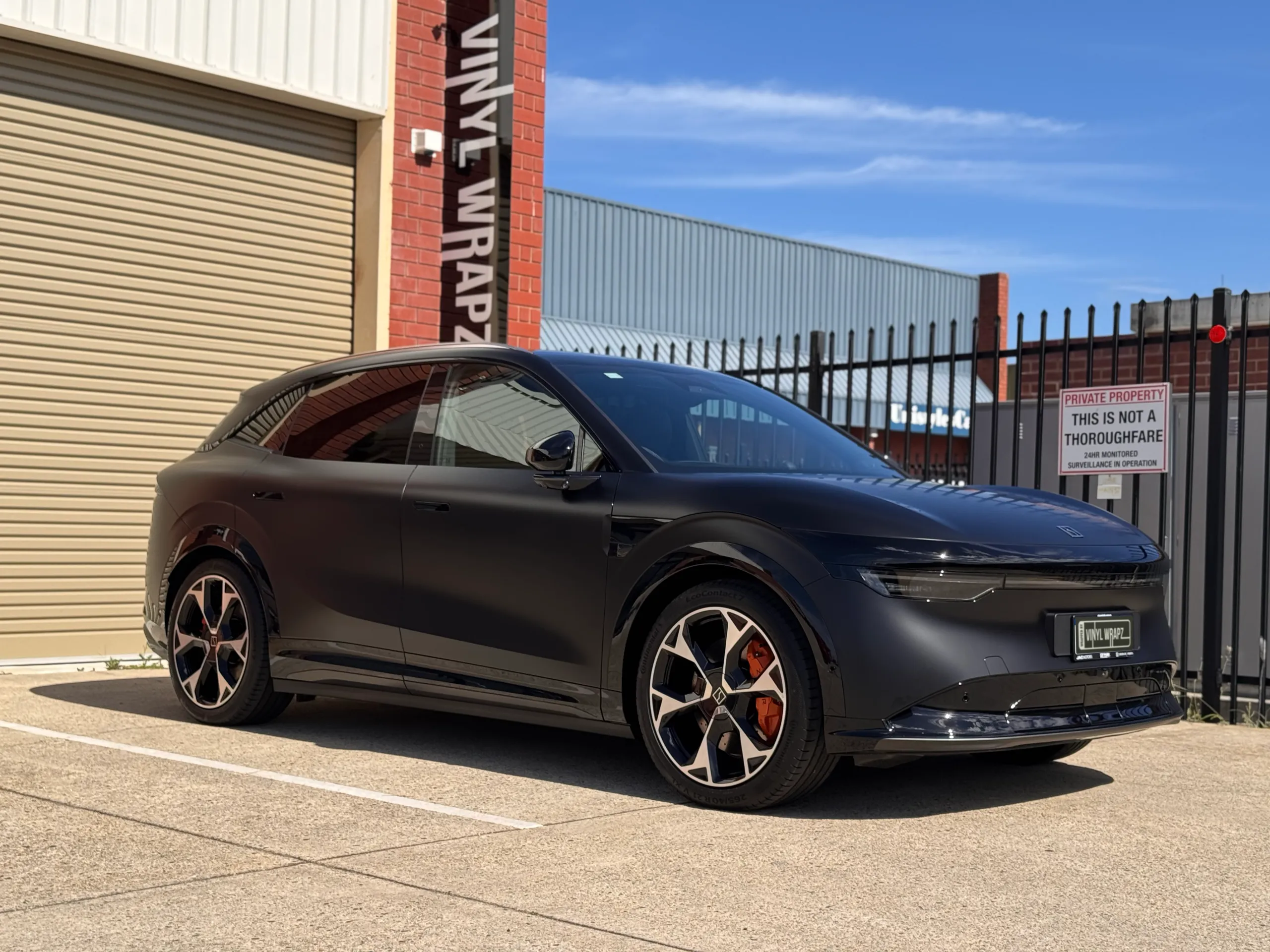 Satin black Zeekr 7X viewed from the front quarter outside the workshop