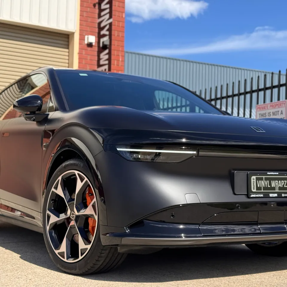 Low front-quarter view of the satin black Zeekr 7X in sunlight