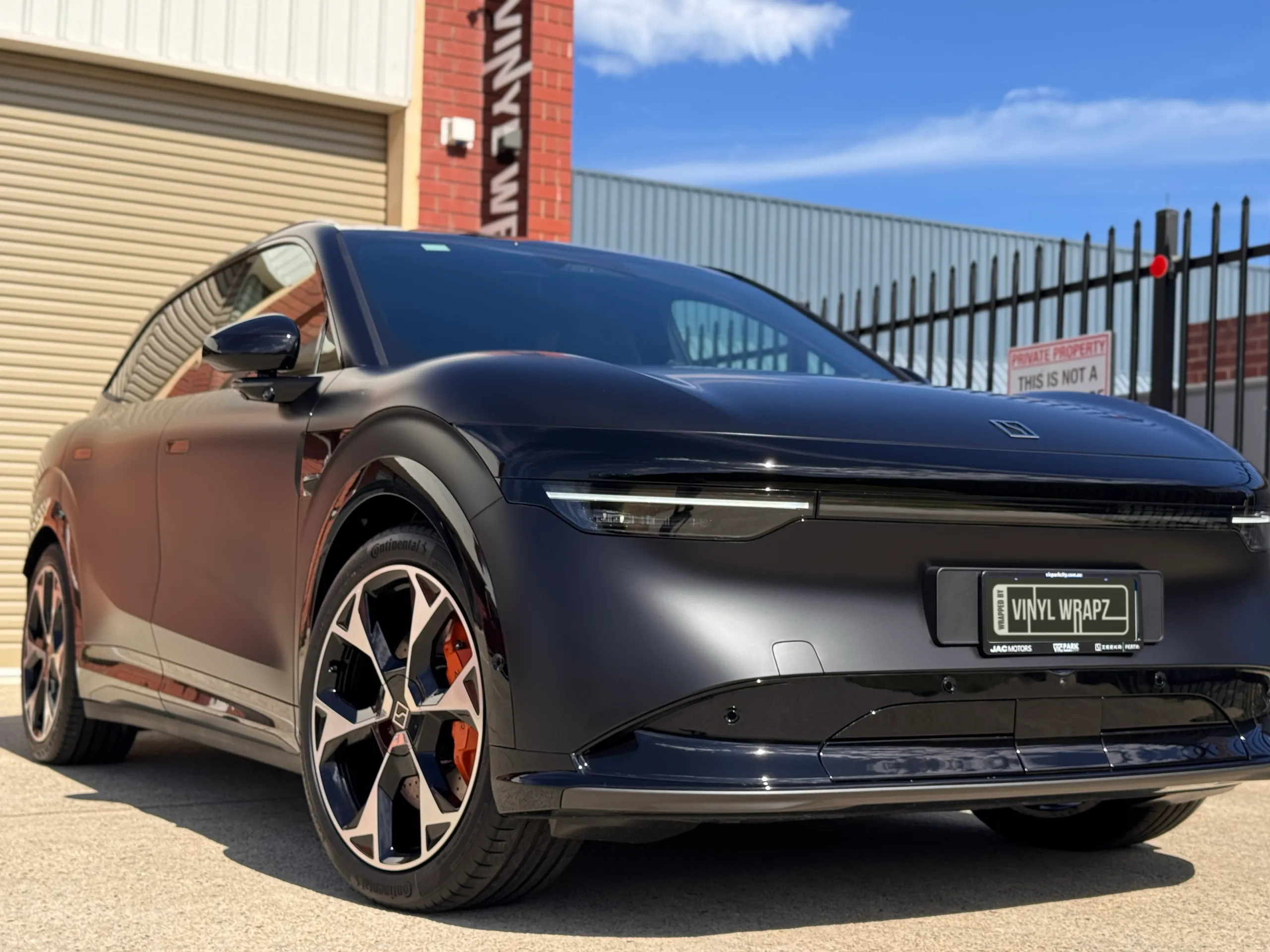 Low front-quarter view of the satin black Zeekr 7X in sunlight